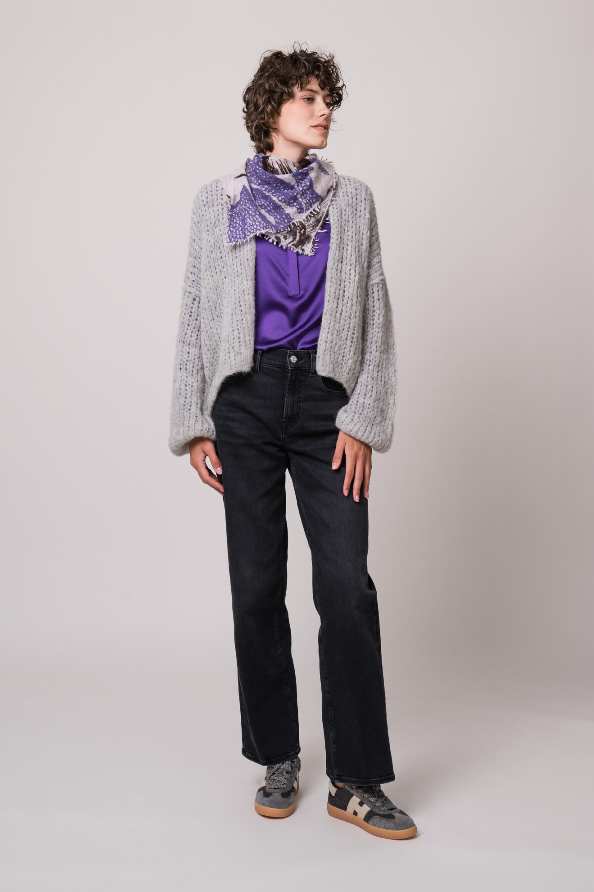Model trägt eine graue Weste der Marke Michele & Hoven, eine violette Bluse der Marke Herzens und eine schwarze Jeans der Marke 7 for all mankind und ein Tuch von Mouleta.