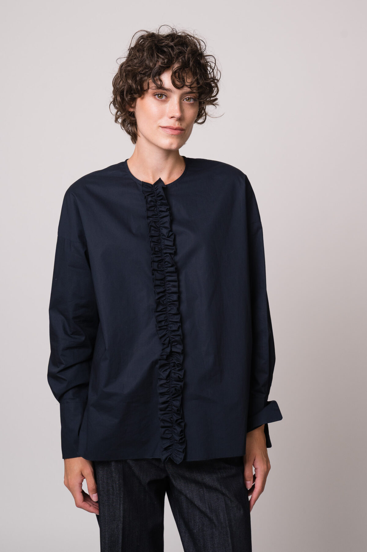 Model trägt eine marine-blaue Bluse der Marke Susanne Bommer und eine Jeans der Marke Mason’s.