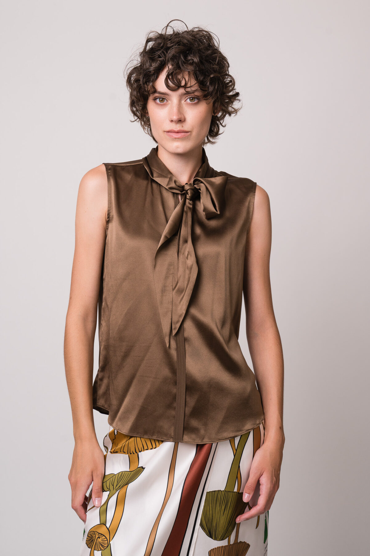 Model trägt eine braune Bluse und einen gemusterten Rock der Marke Dorothee Schumacher.