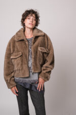 Model trägt eine braune Fake Fur Jacke der Marke Betta Corradi, ein graues Seidentop der Marke Luisa Cerano, einen grau gemusterten Pullover der Marke Grace.