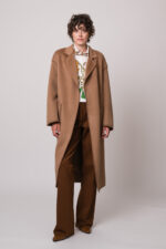 Model trägt einen braunen Mantel der Marke Lou Andrea, eine gemusterte Bluse und eine braune Hose der Marke Dorothee Schumacher.