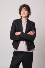 Model trägt eine helle Bluse, einen grauen Blazer und eine graue Hose der Marke Luisa Cerano.