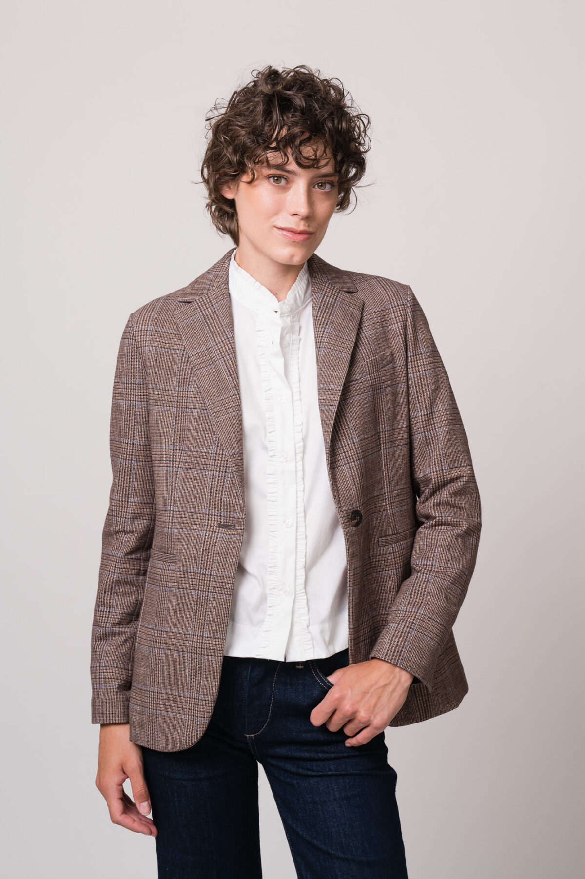 Model trägt einen braun karierten Blazer der Marke Circolo, eine weiße Bluse der Marke Wendy Stark und eine blaue Jeans der Marke True Religion