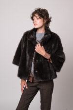 Model trägt eine braune Bluse der Marke The Mercer, einen hellgrau gemusterten Pullunder der Marke Grace sowie eine dunkelbraune Fake Fur Jacke der Marke Luisa Cerano.