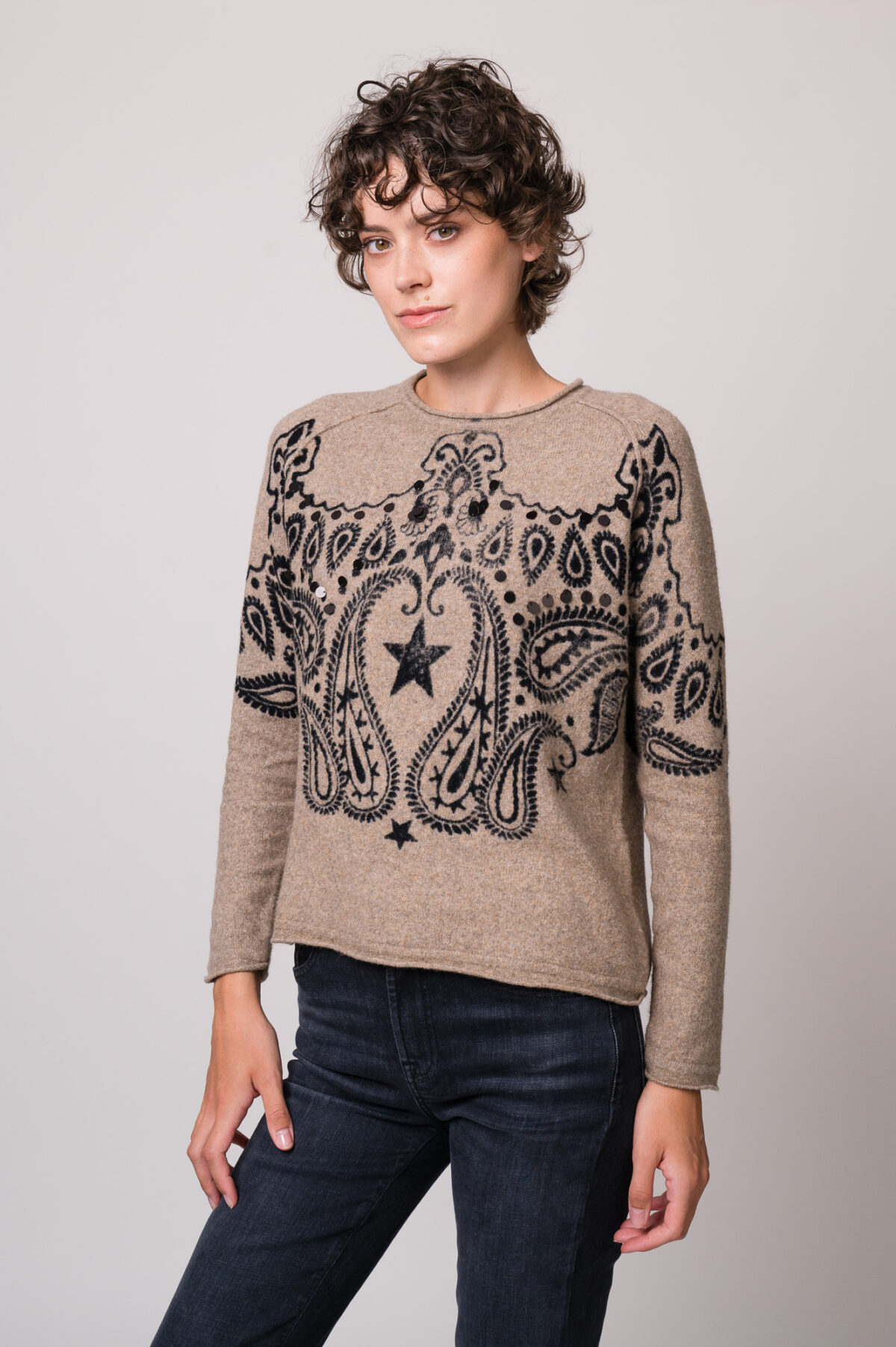 Model trägt einen beige gemusterten Pullover der Marke Grace.