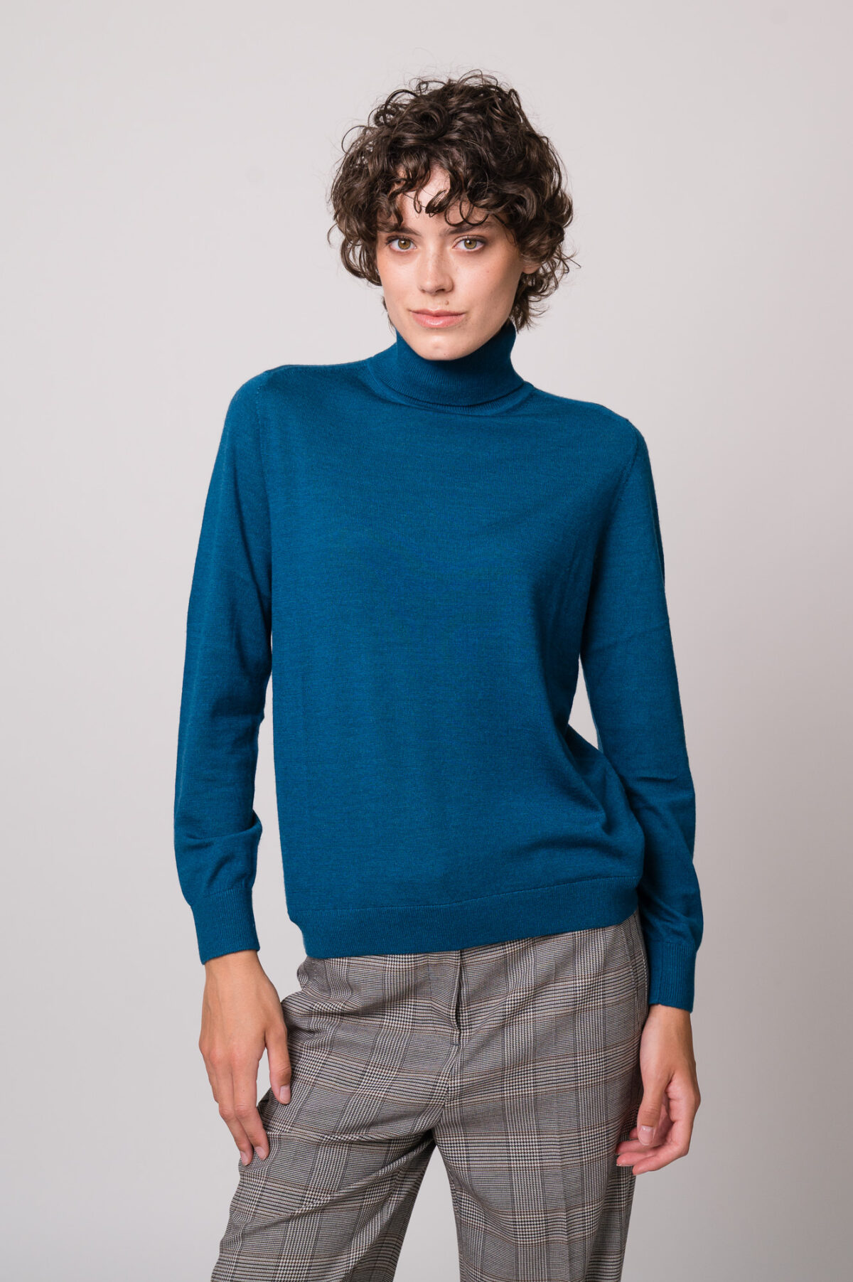 Model trägt einen türkisfarbigen Rollkragenpullover der Marke Luisa Cerano.