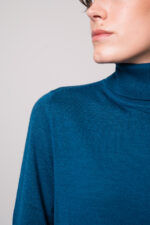 Model trägt einen türkisfarbigen Rollkragenpullover der Marke Luisa Cerano.