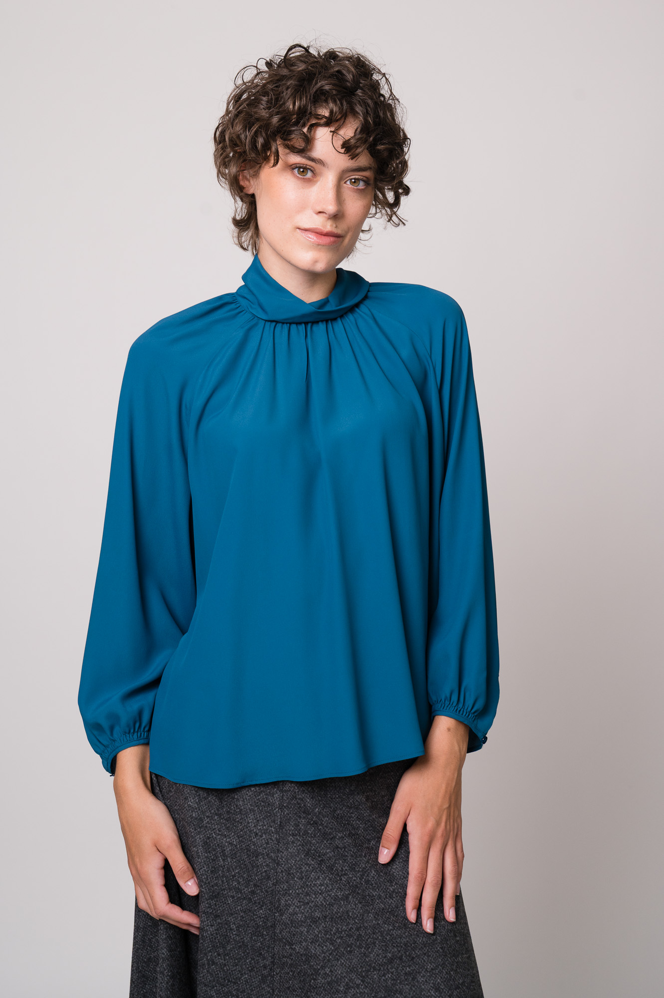 Model trägt eine türkisblaue Bluse der Marke Luisa Cerano.
