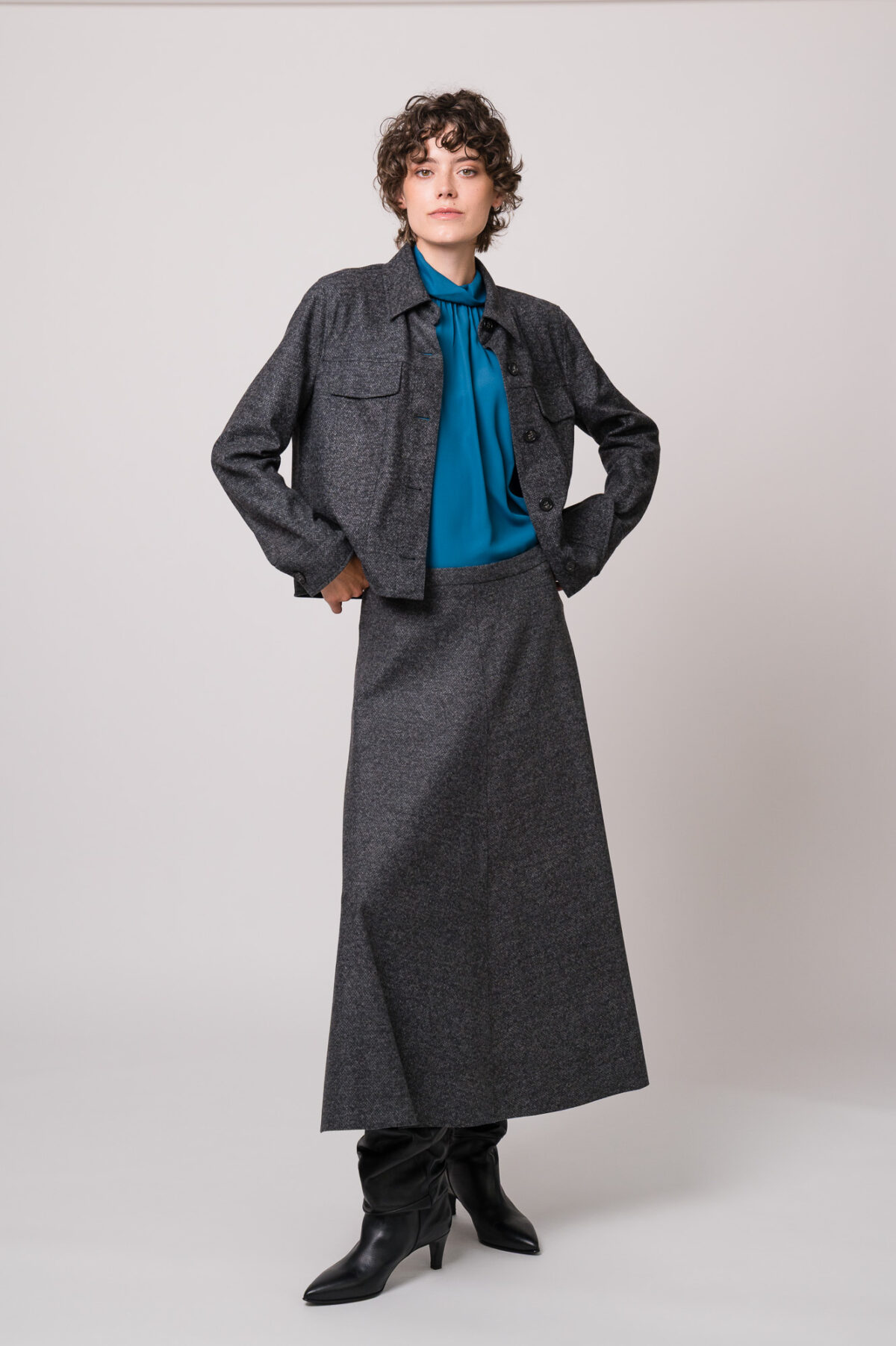 Model trägt eine graue Blazerjacke und einen grauen Rock sowie eine türkisblaue Bluse der Marke Luisa Cerano.
