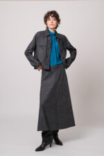 Model trägt eine graue Blazerjacke und einen grauen Rock sowie eine türkisblaue Bluse der Marke Luisa Cerano.