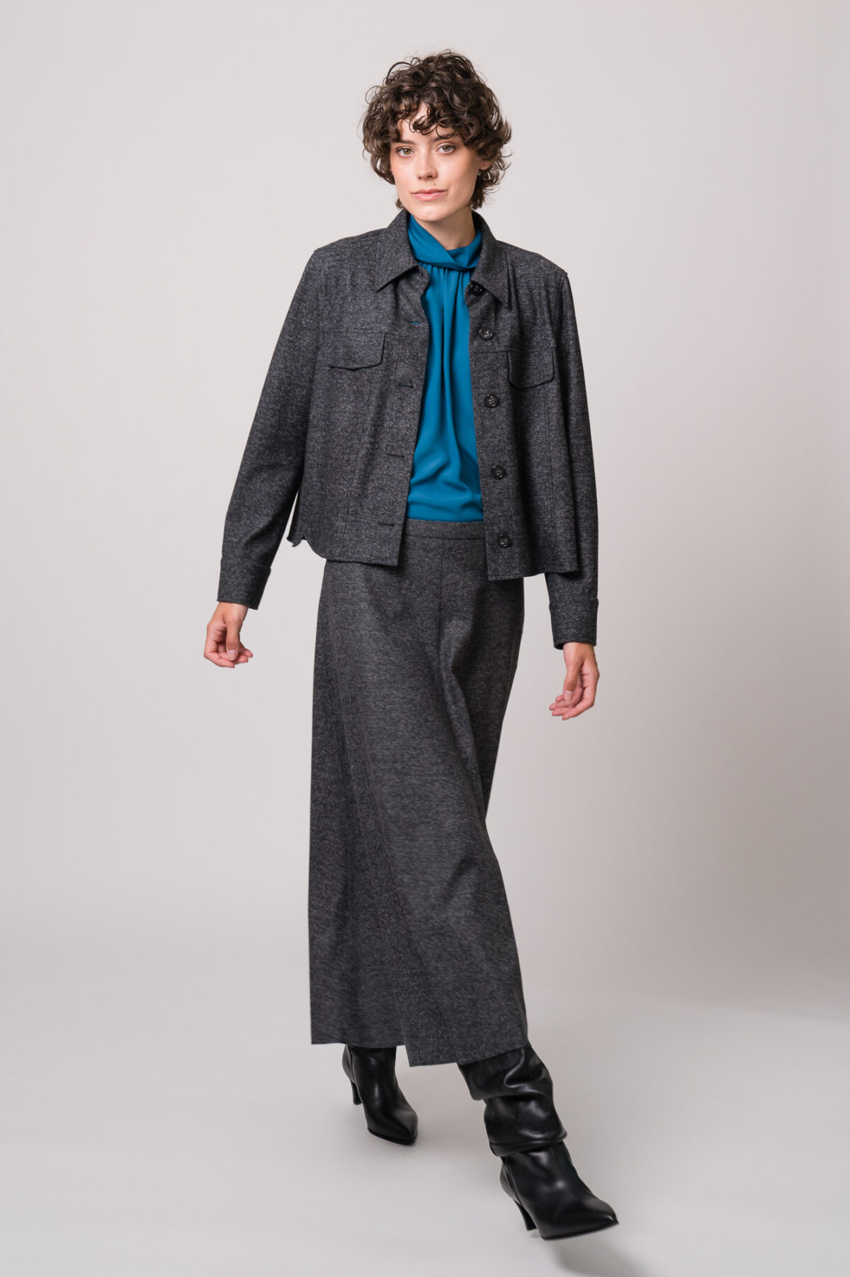 Model trägt eine graue Blazerjacke und einen grauen Rock sowie eine türkisblaue Bluse der Marke Luisa Cerano.