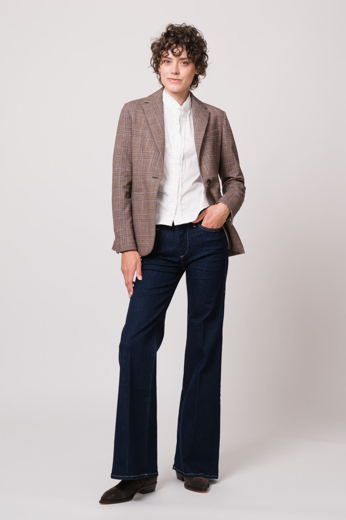 Model trägt einen braunen Blazer der Marke Circolo, eine weiße Bluse der Marke Wendy Stark und eine Jeans der Marke True Religion.
