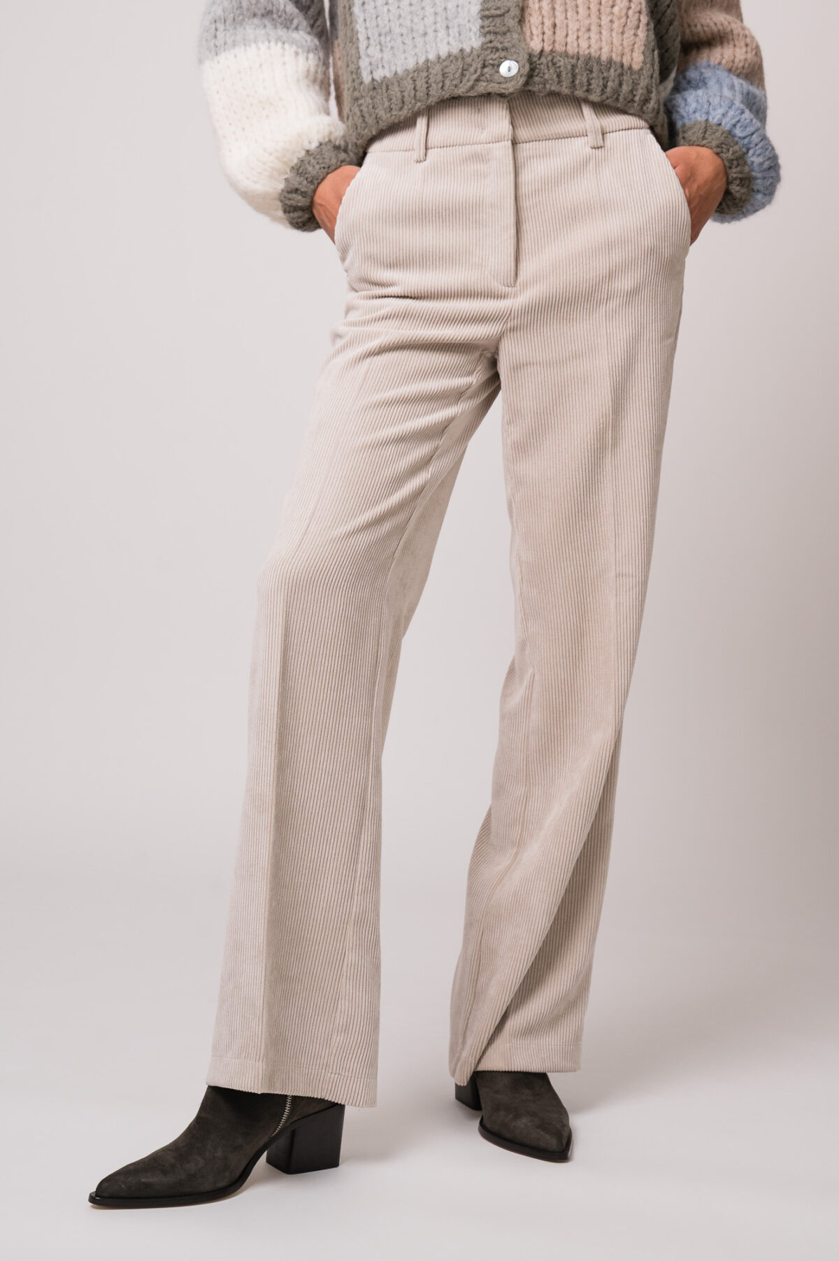 Model trägt eine beige Kordhose der Marke Cambio.