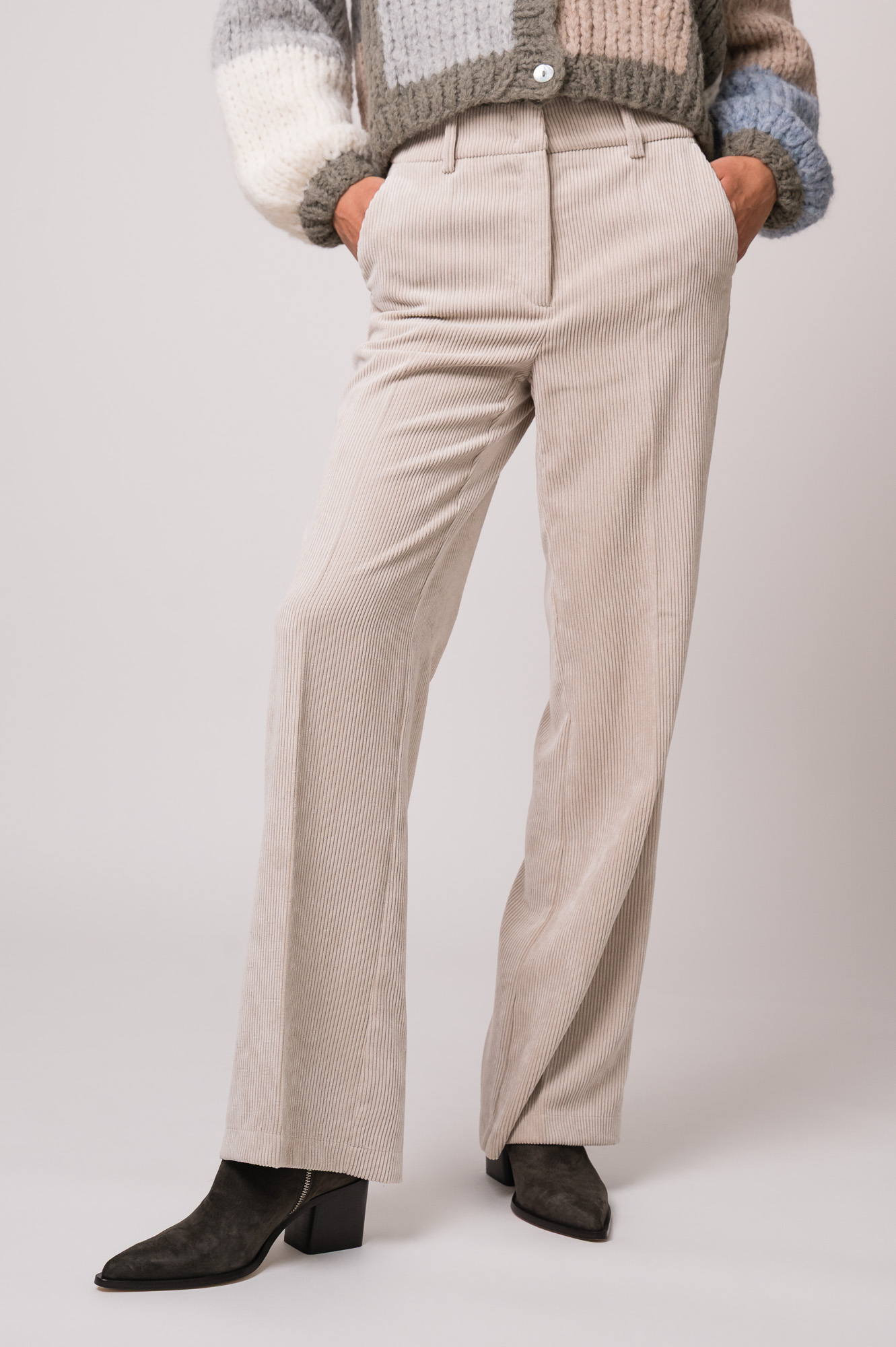 Model trägt eine beige Kordhose der Marke Cambio.