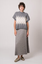 Model trägt einen grau gemusterten Kurzarm-Strickpullover und einen grau karierten Faltenrock der Marke Joop!
