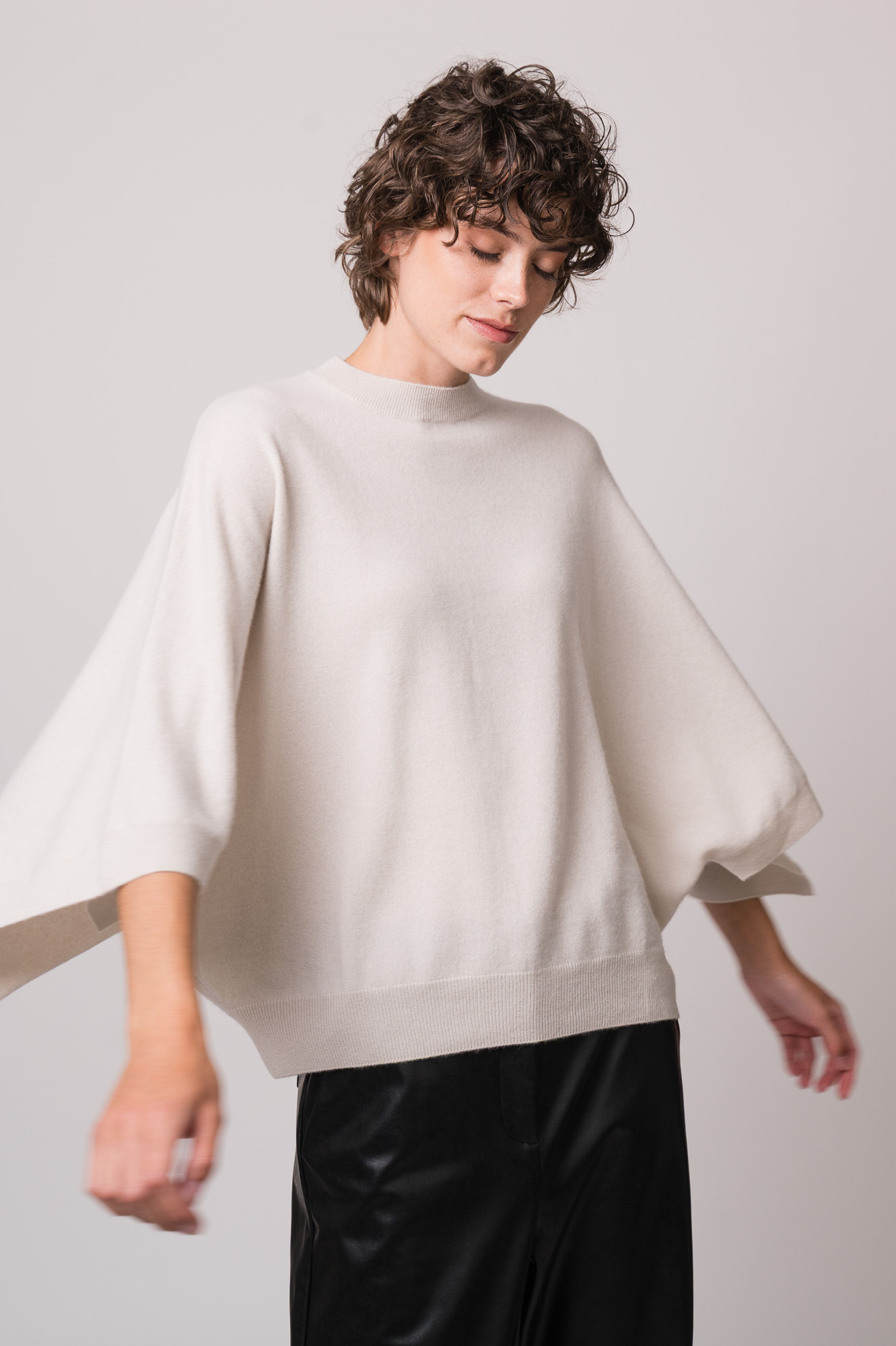 Model trägt einen beigen Pullover der Marke Herzens