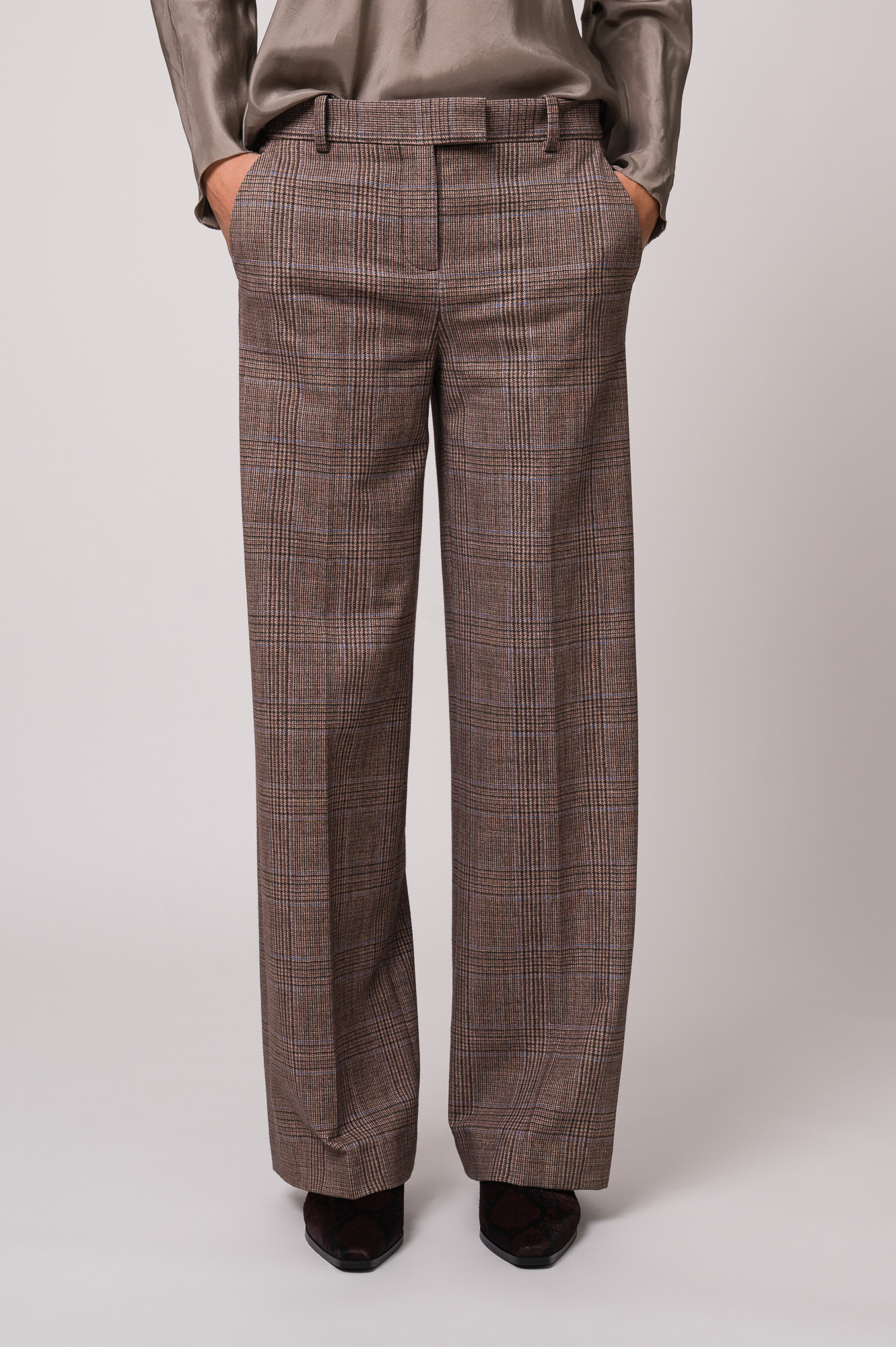 Model trägt eine braun karierte Hose der Marke Circolo.