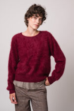 Model trägt einen weinroten Pullover der Marke Susanne Bommer und ein braunes Shirt der Marke Susanne Bommer.