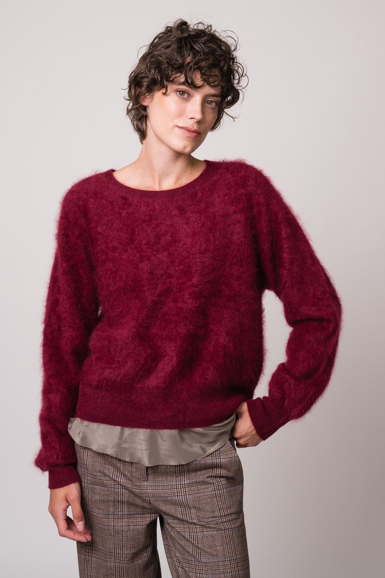 Model trägt einen weinroten Pullover der Marke Susanne Bommer und ein braunes Shirt der Marke Susanne Bommer.