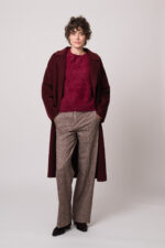 Model trägt einen weinroten Mantel der Marke Lu Li Lina, einen weinroten Pullover der Marke Susanne Bommer, eine braun karierte Hose der Marke Circolo.