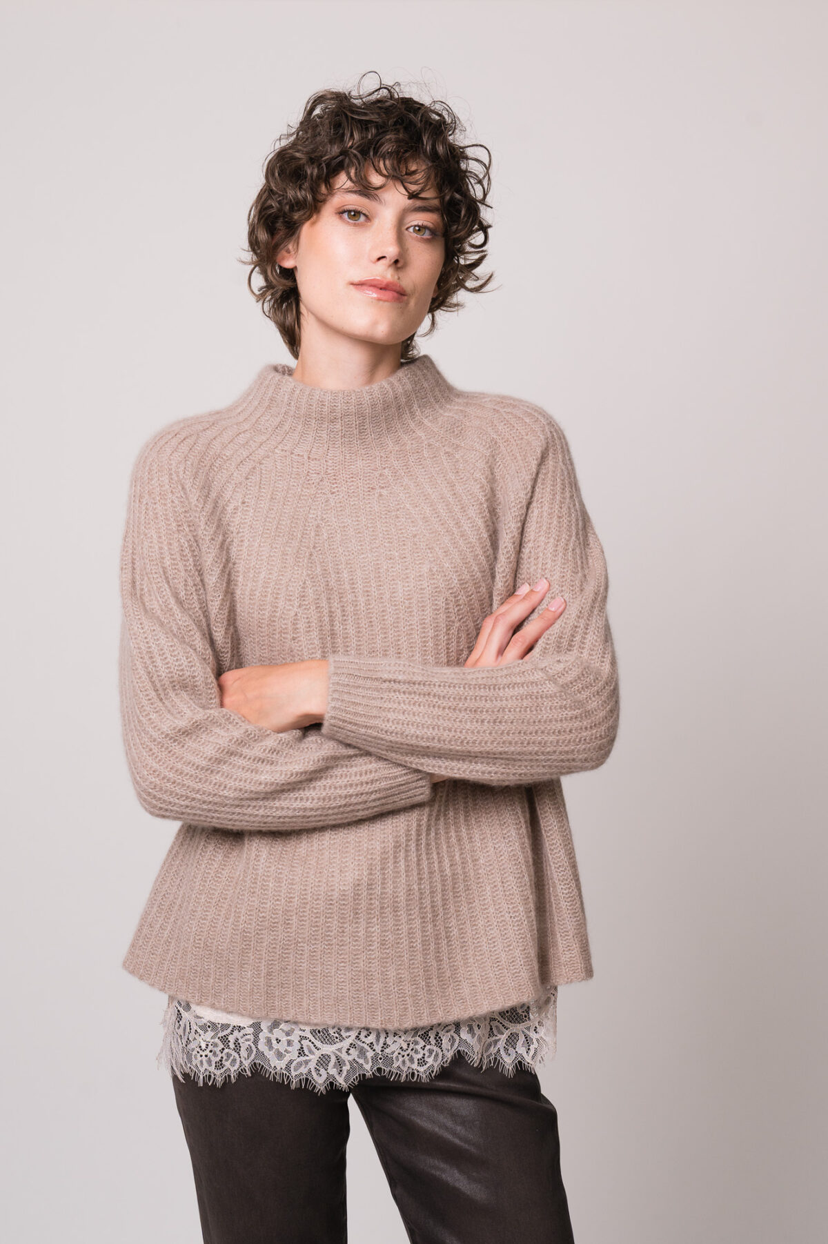 Model trägt eine beiges Top mit Spitze der Marek Allude, einen beigen Pullover der Marke Hemisphere, eine braune Jeans der Marke 7 for all mankind.