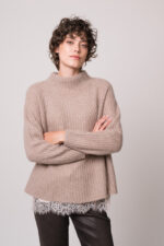 Model trägt eine beiges Top mit Spitze der Marek Allude, einen beigen Pullover der Marke Hemisphere, eine braune Jeans der Marke 7 for all mankind.