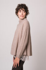 Model trägt eine beiges Top mit Spitze der Marek Allude, einen beigen Pullover der Marke Hemisphere, eine braune Jeans der Marke 7 for all mankind.