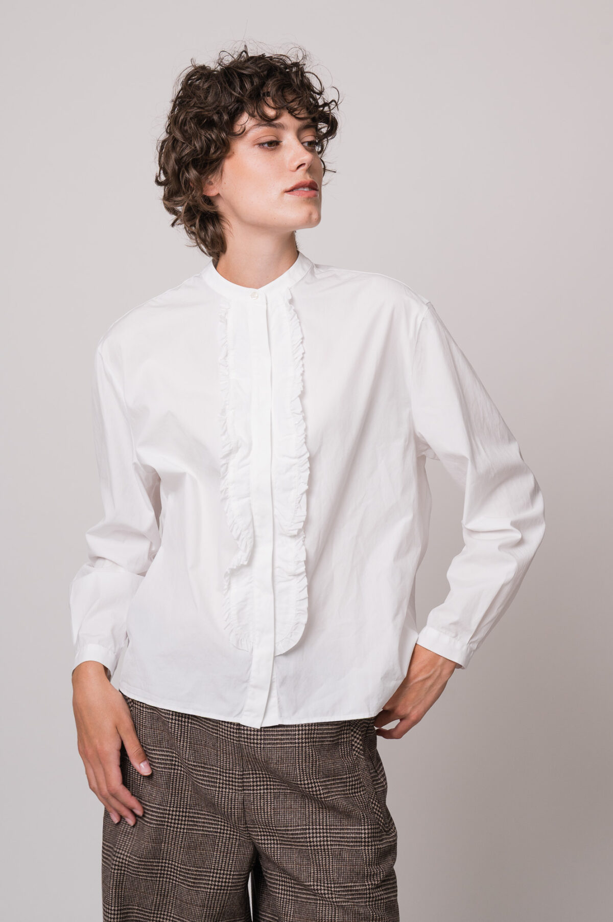 Model trägt eine weiße Bluse der Marke Soluzione, eine braun karierte Hose der Marke Cambio.