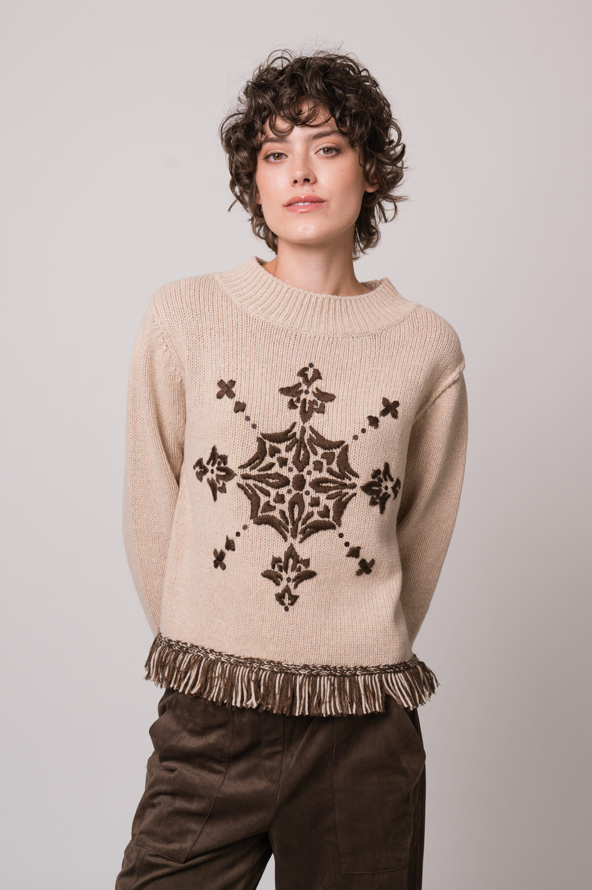 Model trägt einen braun gemusterten Pullover der Marke Grace und eine braune Hose der Marke Cambio.