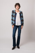 Model trägt eine blau-braune Weste mit Rautenmuster der Marke The Mercer, ein weißes Seidentop der Marke Susanne Bommer, eine blaue Jeans der Marke 7 for all mankind.