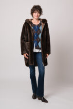 Model trägt eine braune Jacke der Marke Betta Corradi, eine blau-braune Weste mit Rautenmuster der Marke The Mercer, ein weißes Seidentop der Marke Susanne Bommer, eine blaue Jeans der Marke 7 for all mankind.