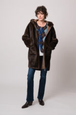 Model trägt eine braune Jacke der Marke Betta Corradi, eine blau-braune Weste mit Rautenmuster der Marke The Mercer, ein weißes Seidentop der Marke Susanne Bommer, eine blaue Jeans der Marke 7 for all mankind.