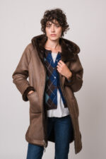 Model trägt eine braune Jacke der Marke Betta Corradi, eine blau-braune Weste mit Rautenmuster der Marke The Mercer, ein weißes Seidentop der Marke Susanne Bommer, eine blaue Jeans der Marke 7 for all mankind.