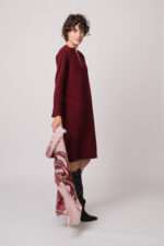 Model trägt ein weinrotes Strickkleid der Marke Rosso35 und eine rosa gemustertes Tuch der Marke Mouleta.