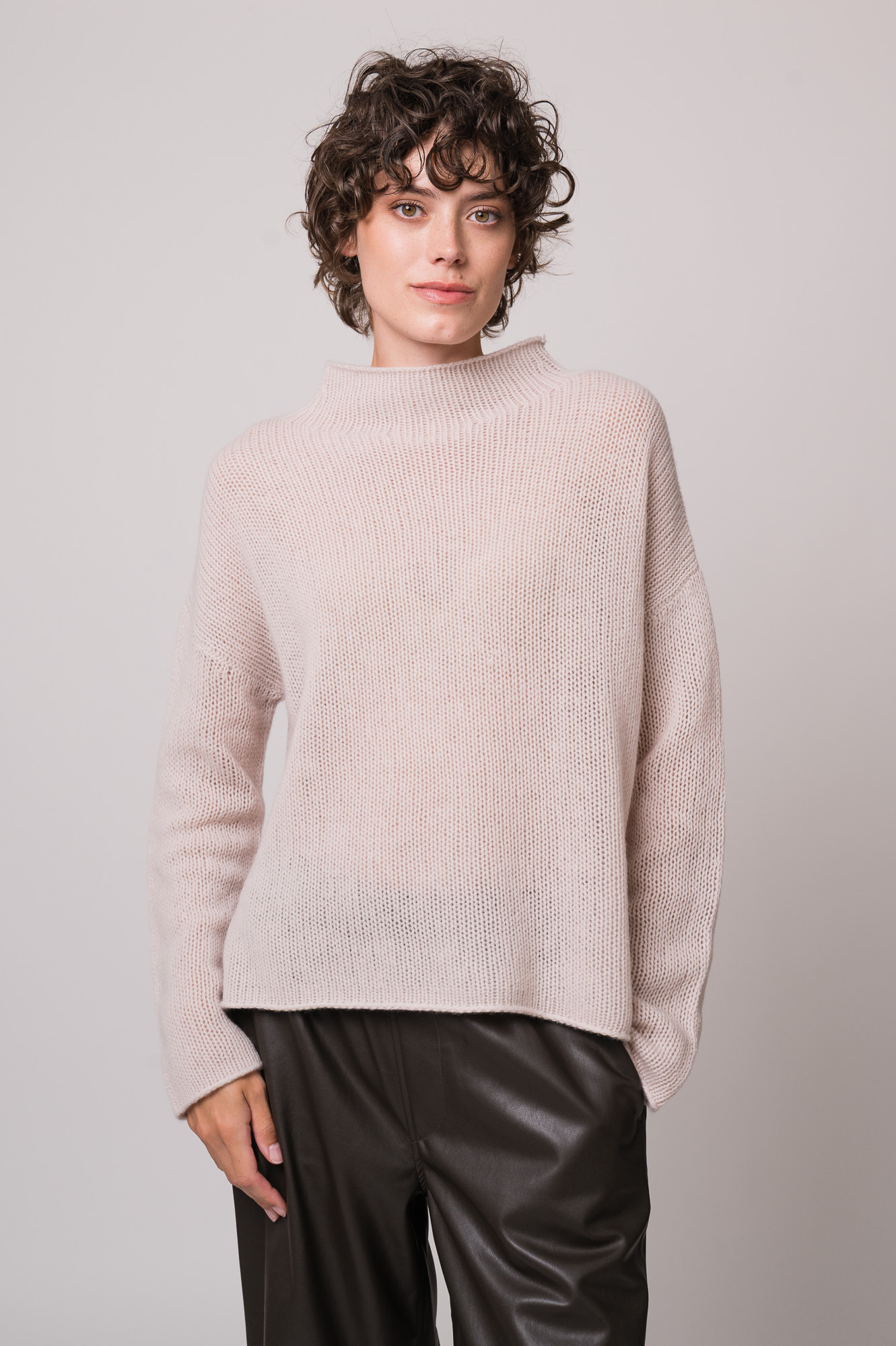 Model trägt einen natur-farbigen Pullover der Marke FFC und eine braune Hose der Marke Lis Lareida.