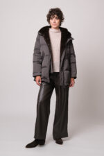 Model trägt eine dunkle Jacke der Marke Lou Andrea, einen natur-farbigen Pullover der Marke FFC und eine braune Hose der Marke Lis Lareida.
