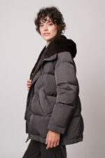 Model trägt eine dunkle Jacke der Marke Lou Andrea, einen natur-farbigen Pullover der Marke FFC und eine braune Hose der Marke Lis Lareida.