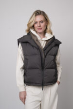 Das Model trägt einen Lounge-Pullover der Marke Unartig mit einem Motiv sowie eine Hose von Cambio in Natur und ein Gilet der Marke Lou Andrea in Anthrazit.