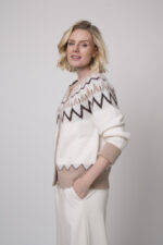 Das Model trägt eine gemusterte Strickweste von Sosue und eine Hose von Cambio in Natur.