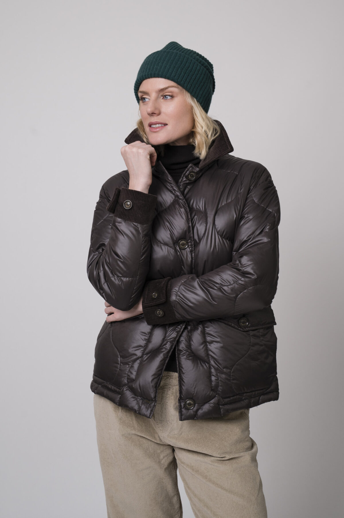 Das Model trägt einen braunen Rollkragenpullover von FFC und eine sandfarbene Cordhose von Joop. Die braune Daunenjacke stammt von Helmur.