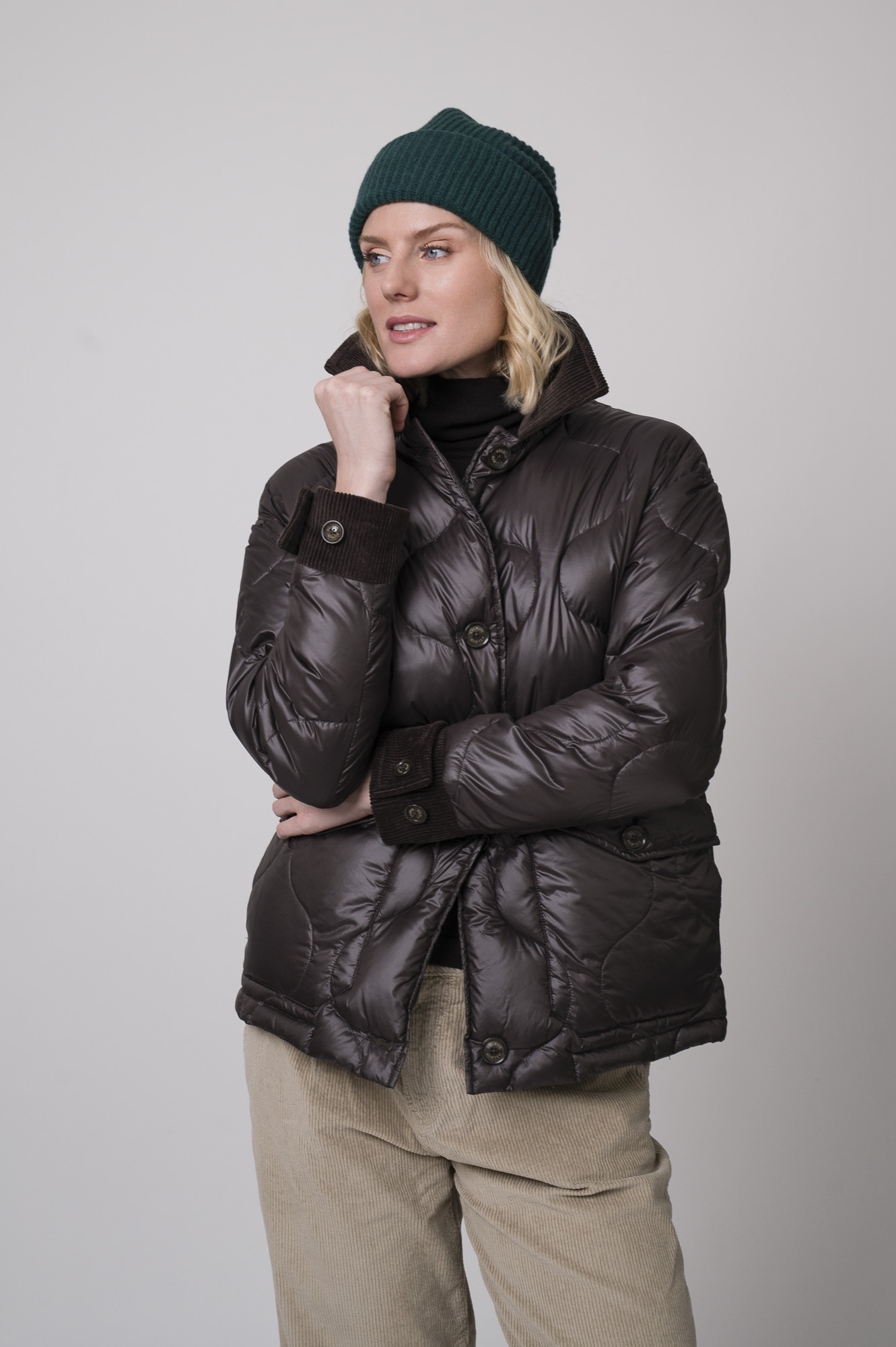 Das Model trägt einen braunen Rollkragenpullover von FFC und eine sandfarbene Cordhose von Joop. Die braune Daunenjacke stammt von Helmur.