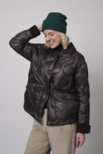 Das Model trägt einen braunen Rollkragenpullover von FFC und eine sandfarbene Cordhose von Joop. Die braune Daunenjacke stammt von Helmur.