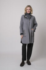 Das Model trägt einen Stehkragenpullover von Luisa Cerano, eine anthrazitfarbene, karierte Hose von Cambio und eine mittelgraue Jacke von Helmur.