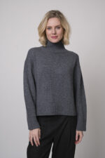 Das Model trägt einen Stehkragenpullover von Luisa Cerano und eine anthrazitfarbene, karierte Hose von Cambio.