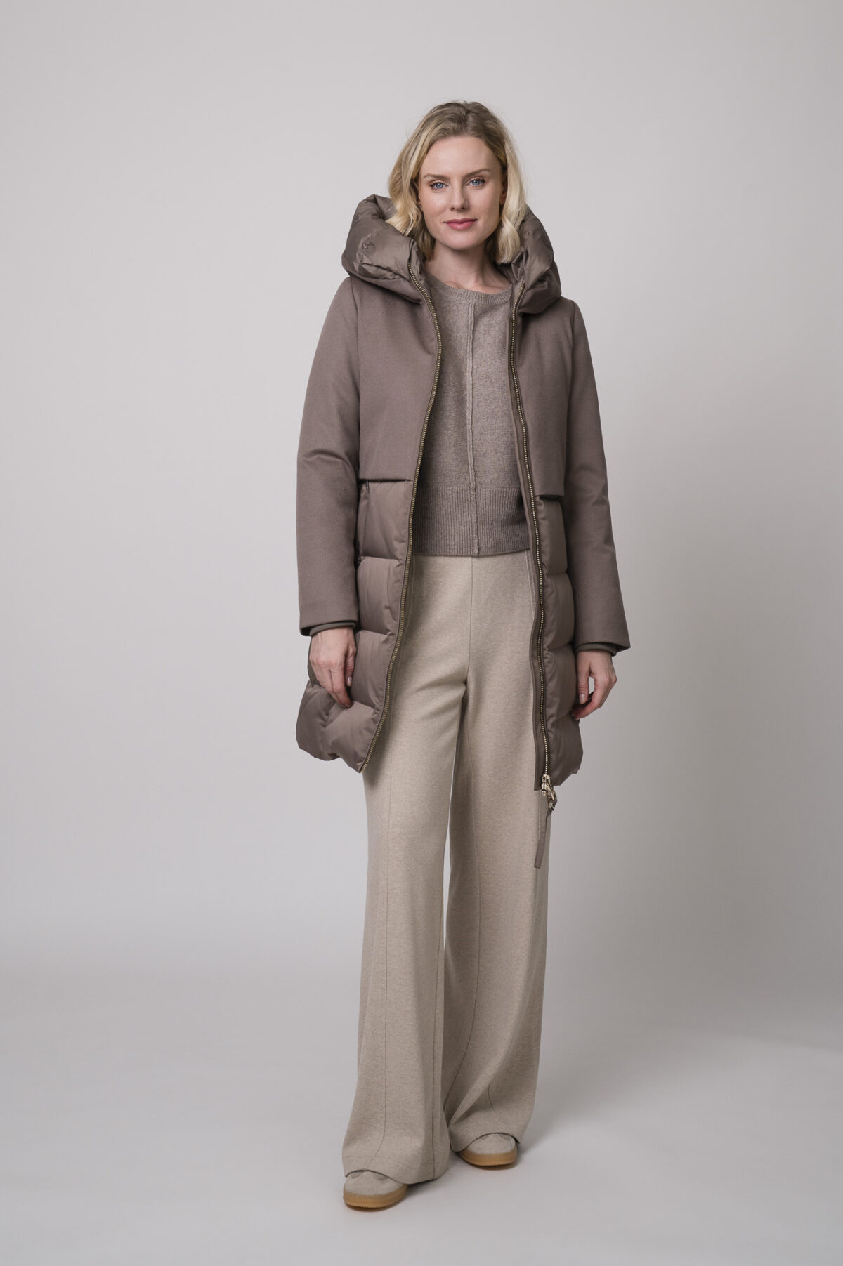 Das Model trägt eine Hose der Marke Cambio in Sand, einen braunen Pullover der Marke Sosue und eine braune Jacke der Marke Duno.