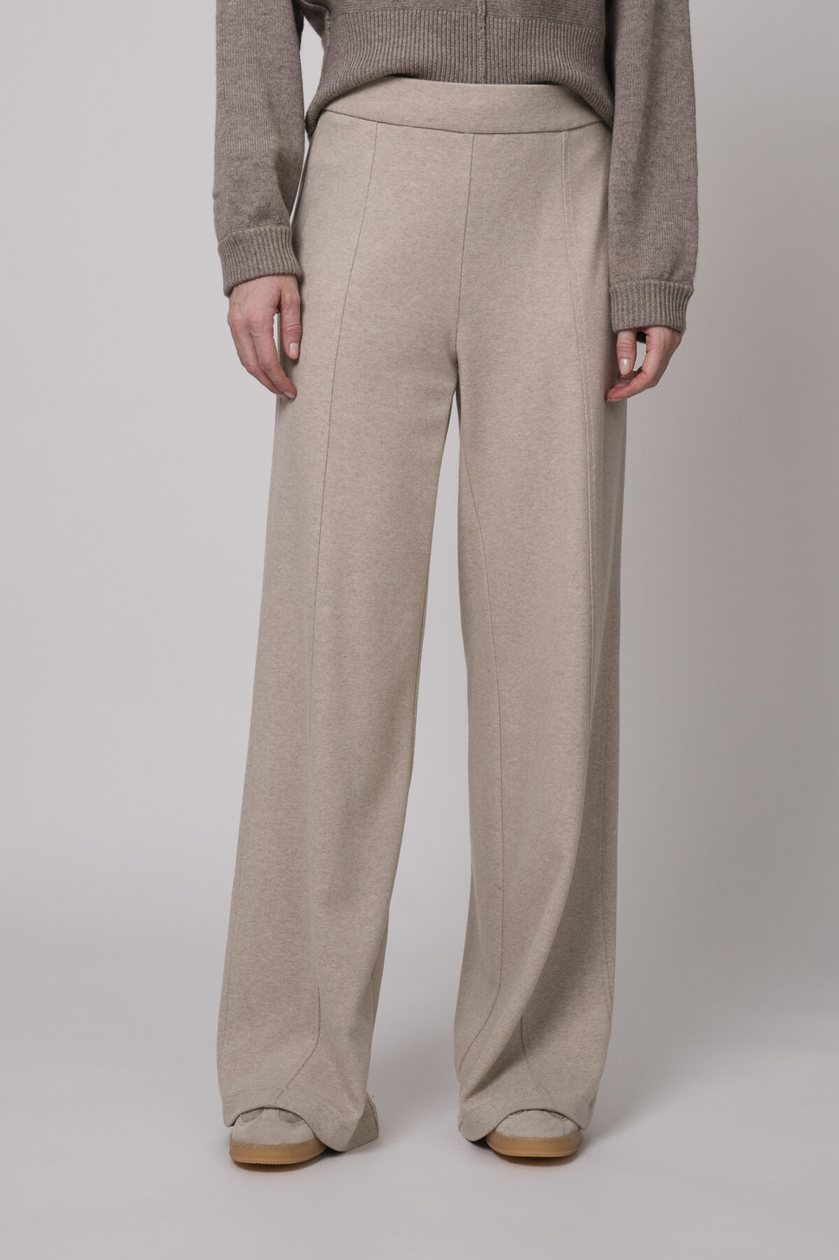 Das Model trägt eine Hose der Marke Cambio in Sand und einen braunen Pullover der Marke Sosue.
