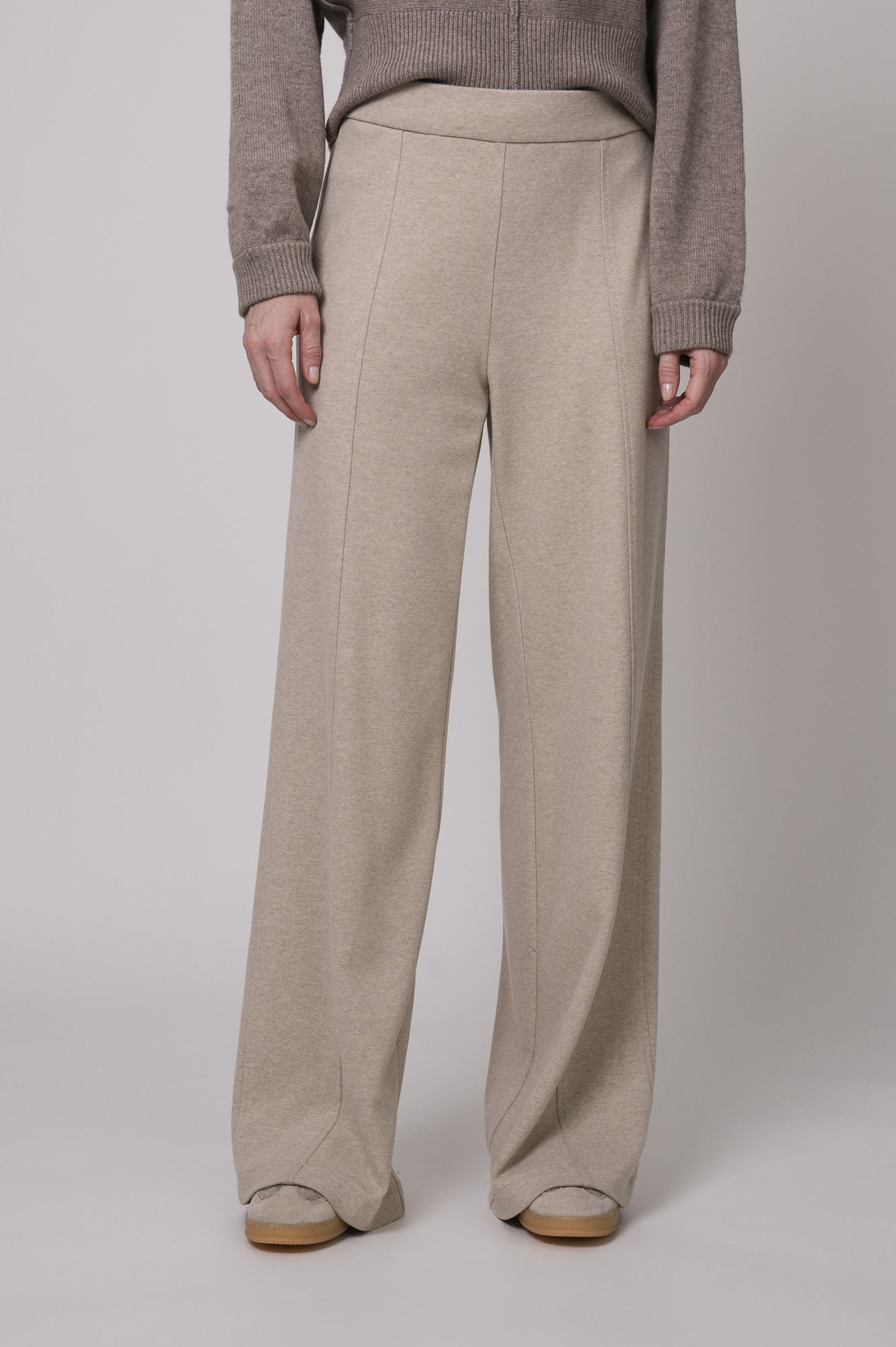 Das Model trägt eine Hose der Marke Cambio in Sand und einen braunen Pullover der Marke Sosue.