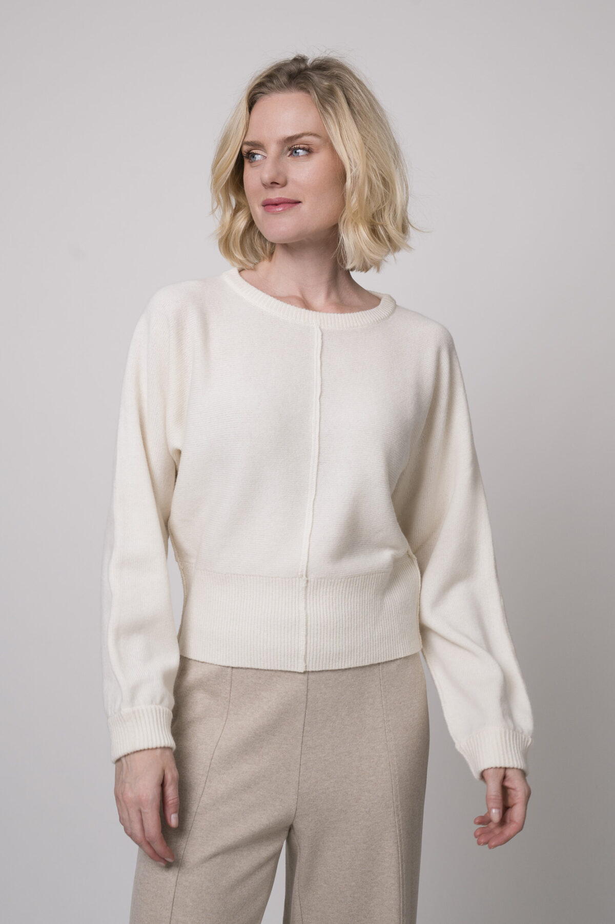 Das Model trägt einen Pullover der Marke Sosue in der Farbe Natur, dazu eine Hose der Marke Cambio in Sand.