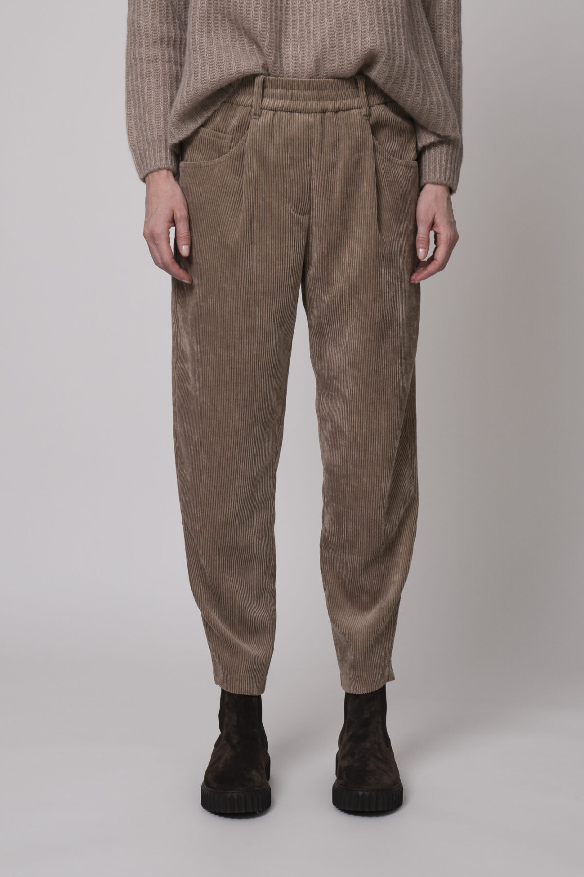 Das Model trägt einen Stehkragenpullover von Hemisphere in Sand, dazu eine Cordhose von Cambio in Camel.