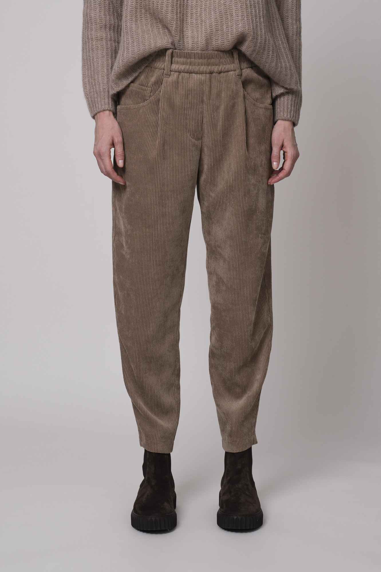 Das Model trägt einen Stehkragenpullover von Hemisphere in Sand, dazu eine Cordhose von Cambio in Camel.